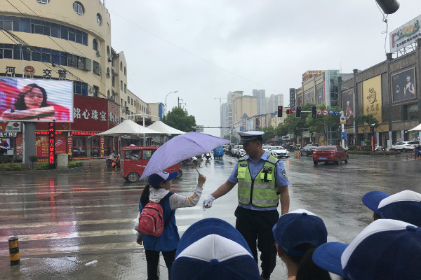 图为：新华小记者宋柯茗为雨中执勤的交警叔叔撑伞.jpg