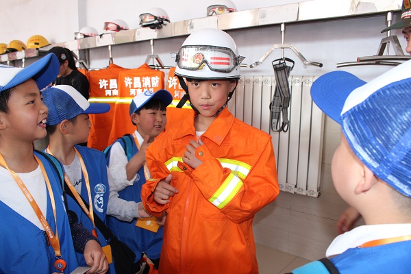 图为：新华小记者体验穿戴消防服.JPG